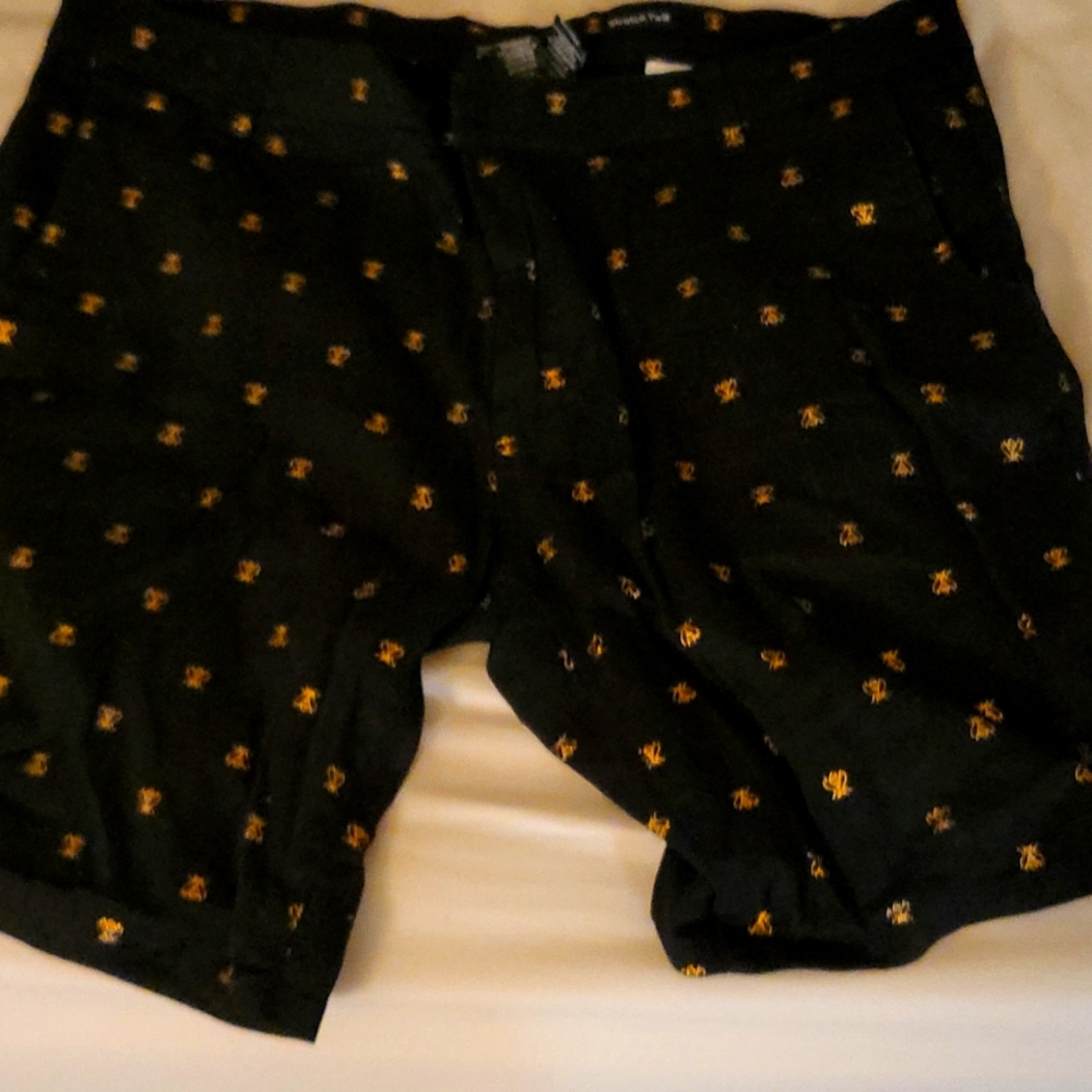 A pair of dress shorts with golden bess on th